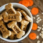 Carrot and cheese dog treats on wooden board with sliced carrot and rolled oats