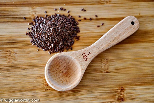 Flax seeds and wooden measuring spoon on bamboo cutting board Flax seeds and wooden measuring spoon on bamboo cutting board