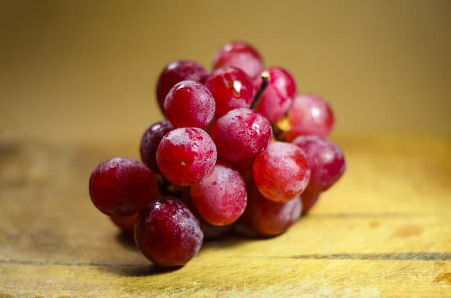 A bunch of red grapes on a wooden board