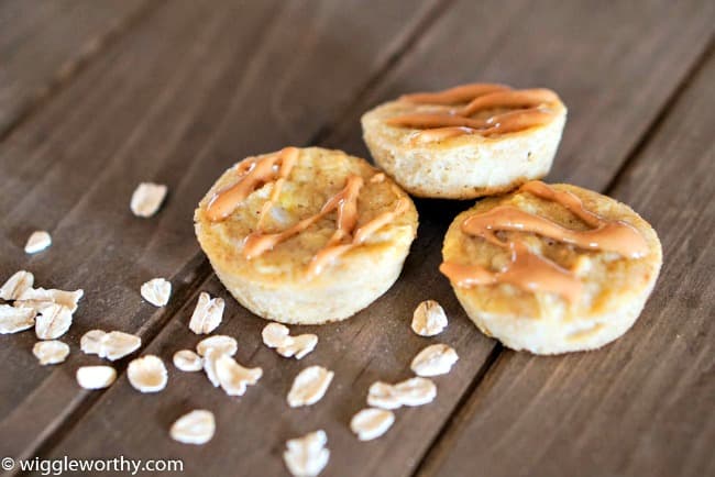 Peanut butter and applesauce pupcakes on wooden board with rolled oats sprinkled around them Peanut butter and applesauce pupcakes on wooden board with rolled oats sprinkled around them