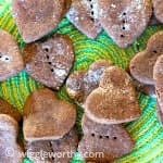 Heart shaped peanut butter and carob dog treats on green place mat