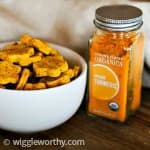 Pumpkin and turmeric dog treats in white bowl next to turmeric spice jar